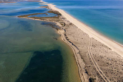 Aerial view of Praia da Fuseta a long sandy barrier island with dunes and clear turquoise waters of the Ria Formosa lagoon in Fuseta Faro District Portugal. Aerial view of Praia da Fuseta a long sandy barrier island with dunes and clear turquoise waters of the Ria Formosa lagoon in Fuseta Faro District Portugal.