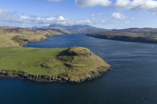 Aerial view of Gesto Bay Viewpoint featuring lush green hills and distant mountain peaks under a blue sky Isle of Skye Scotland United Kingdom.