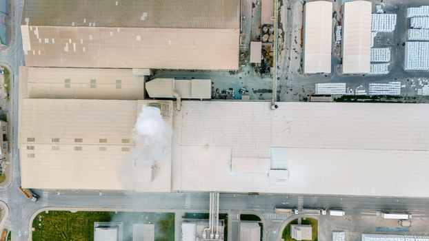 Aerial view of an industrial complex featuring large factory rooftops and a smoking chimney in Sabac Vojvodina Serbia. Aerial view of an industrial complex featuring large factory rooftops and a smoking chimney in Sabac Vojvodina Serbia.