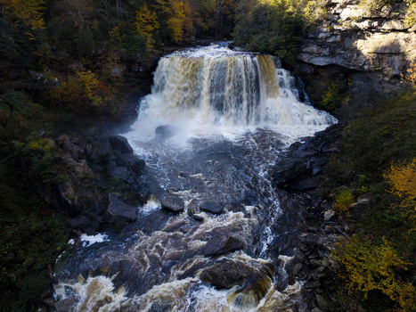 Aerial view of Blackwater Falls cascading over rocky cliffs surrounded by vibrant autumn foliage in Blackwater Falls State Park in Davis West Virginia United States.