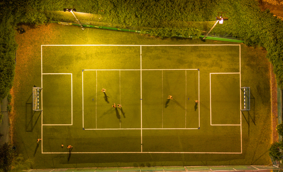 Aerial view of a soccer field at night illuminated by bright floodlights with people playing on the green turf in Tel Aviv Yafo Tel Aviv District Israel. Aerial view of a soccer field at night illuminated by bright floodlights with people playing on the green turf in Tel Aviv Yafo Tel Aviv District Israel.