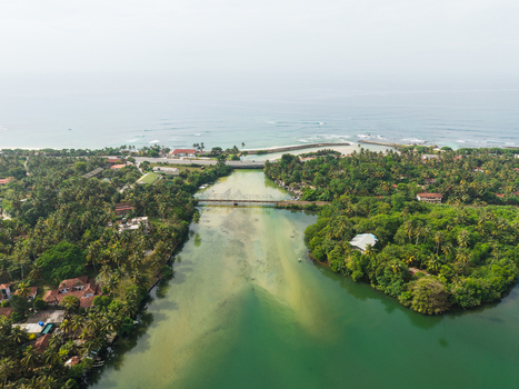 Aerial view of the Koggala river flowing into the Indian Ocean with a bridge and lush tropical vegetation Koggala Southern Province Sri Lanka. Aerial view of the Koggala river flowing into the Indian Ocean with a bridge and lush tropical vegetation Koggala Southern Province Sri Lanka.