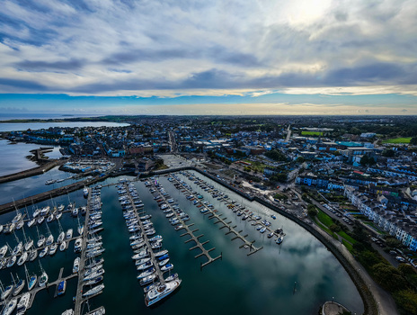 Aerial view of Bangor Harbour and Town with boats in the marina surrounded by coastal buildings and green landscapes under a cloudy sky in Bangor Northern Ireland United Kingdom.