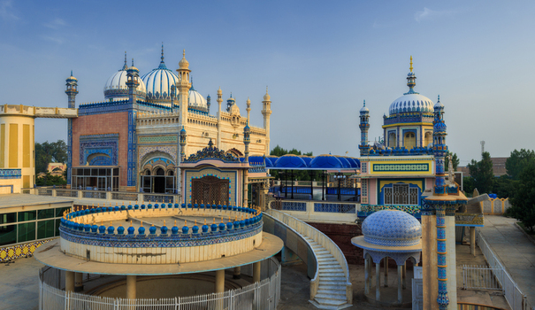 View of the ornate Jamia Masjid Bhong Sharif with its intricate blue and white tile work domes and decorative architectural features in Bhong Punjab Pakistan.