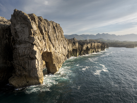 Aerial view of the rugged coastal cliffs and natural stone arch formation along the Cantabrian Sea in Nueva Asturias Spain.