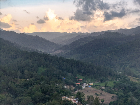 Aerial view of the lush mountainous landscape with dense forests rolling hills scattered houses and a sunset sky in Jarabacoa La Vega Province Dominican Republic.