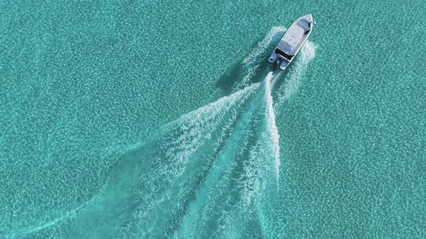 Aerial view of a motorboat cruising through turquoise water Maldives.
