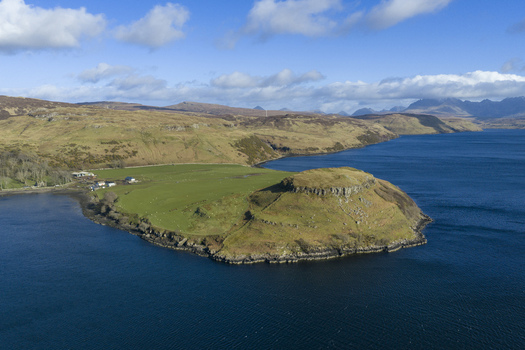 Aerial view of the rugged coastline at Gesto Bay Viewpoint featuring green pastures and rocky cliffs overlooking the deep blue sea Isle of Skye Scotland United Kingdom.