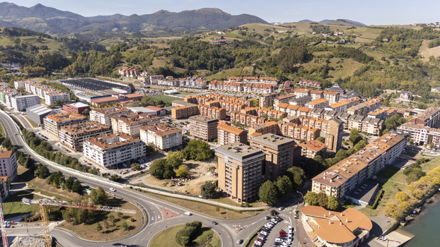 Aerial view of the town of Zumaia with its residential apartment blocks winding roads a roundabout and lush green hills in Zumaia Basque Country Spain.