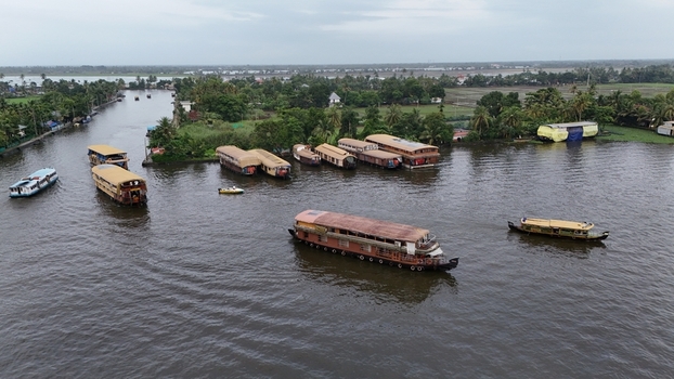 Aerial view of traditional houseboats moored along the Alleppey Backwaters surrounded by lush green palm trees and calm water in Alappuzha Kerala India. Aerial view of traditional houseboats moored along the Alleppey Backwaters surrounded by lush green palm trees and calm water in Alappuzha Kerala India.