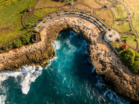 Aerial view of the rugged coastline at Devil s Tears with turquoise waves crashing against rocky cliffs and a landscaped park area Kecamatan Nusa Penida Bali Indonesia. Aerial view of the rugged coastline at Devil s Tears with turquoise waves crashing against rocky cliffs and a landscaped park area Kecamatan Nusa Penida Bali Indonesia.