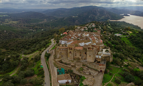 Aerial view of a medieval castle perched atop a hill overlooking the rolling hills and a glistening lake Castellar de la Frontera Andalusia Spain. Aerial view of a medieval castle perched atop a hill overlooking the rolling hills and a glistening lake Castellar de la Frontera Andalusia Spain.