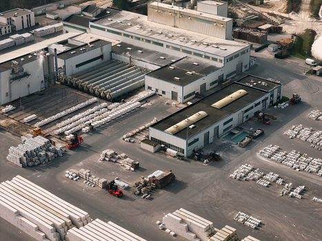 Aerial view of an industrial facility with warehouse buildings rows of stacked construction materials and forklifts in the yard in Dulmen North Rhine Westphalia Germany. Aerial view of an industrial facility with warehouse buildings rows of stacked construction materials and forklifts in the yard in Dulmen North Rhine Westphalia Germany.