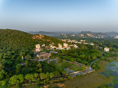 Aerial view of lush green hills residential buildings and a serene lake in the outskirts of Udaipur Rajasthan India.