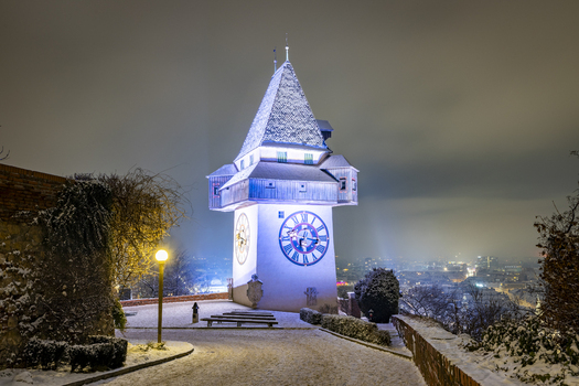 View of the iconic clock tower standing majestically amidst a snowy landscape its illuminated face casting an ethereal glow on the quiet scene Graz Styria Austria. View of the iconic clock tower standing majestically amidst a snowy landscape its illuminated face casting an ethereal glow on the quiet scene Graz Styria Austria.