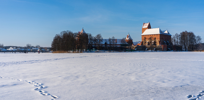 View of Trakai Island Castle surrounded by a vast snow covered frozen lake under a clear blue sky in Trakai Vilnius County Lithuania. View of Trakai Island Castle surrounded by a vast snow covered frozen lake under a clear blue sky in Trakai Vilnius County Lithuania.