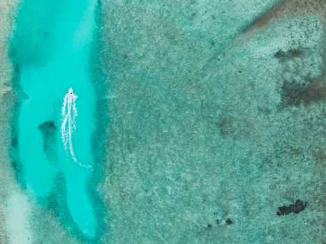 Aerial view of a boat slicing through the turquoise waters near Vashafaru Island creating a stark contrast against the surrounding coral reefs Vashafaru Island Thiladhummathi Atoll Maldives. Aerial view of a boat slicing through the turquoise waters near Vashafaru Island creating a stark contrast against the surrounding coral reefs Vashafaru Island Thiladhummathi Atoll Maldives.