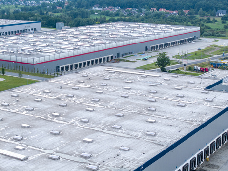 Aerial view of a large logistics hub with expansive warehouse rooftops numerous loading docks and surrounding green landscape in Skawina Lesser Poland Voivode Poland. Aerial view of a large logistics hub with expansive warehouse rooftops numerous loading docks and surrounding green landscape in Skawina Lesser Poland Voivode Poland.