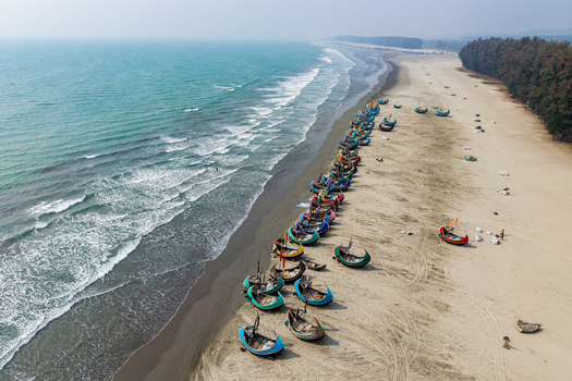 Cox s Bazar Bangladesh 10 March 2026 Aerial view of traditional colorful moon boats lined up on the sandy shore of the world s longest natural sea beach with turquoise waves and pine trees. Cox s Bazar Bangladesh 10 March 2026 Aerial view of traditional colorful moon boats lined up on the sandy shore of the world s longest natural sea beach with turquoise waves and pine trees.