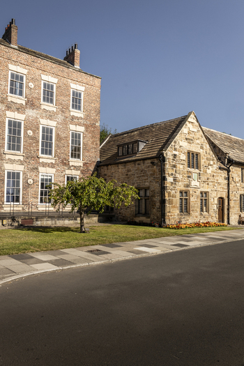 View of historic brick and stone buildings with a small tree on a sunny day in Durham England United Kingdom. View of historic brick and stone buildings with a small tree on a sunny day in Durham England United Kingdom.