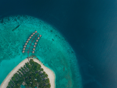 Aerial view of a tropical island fringed by white sand and turquoise waters with overwater bungalows stretching into the deep blue sea Hoarafushi Maldives. Aerial view of a tropical island fringed by white sand and turquoise waters with overwater bungalows stretching into the deep blue sea Hoarafushi Maldives.