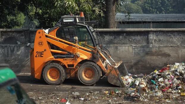 View of an orange loader clearing garbage in Bogura Bangladesh. View of an orange loader clearing garbage in Bogura Bangladesh.