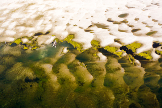 Bogura Bangladesh 06 March 2022 Aerial view of the riverbed featuring intricate sandbars patches of green vegetation and small traditional boats navigating the shallow waters.