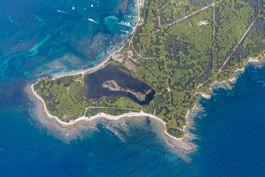 Aerial view of the Ile Sainte Marguerite featuring dense pine forests a central lagoon and rocky coastlines surrounded by the Mediterranean Sea Cannes Provence Alpes Cote d Azur France. Aerial view of the Ile Sainte Marguerite featuring dense pine forests a central lagoon and rocky coastlines surrounded by the Mediterranean Sea Cannes Provence Alpes Cote d Azur France.