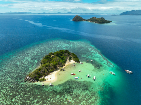 Aerial view of CYC Beach with turquoise waters coral reefs and traditional outrigger boats surrounding the small island in Coron Mimaropa Philippines. Aerial view of CYC Beach with turquoise waters coral reefs and traditional outrigger boats surrounding the small island in Coron Mimaropa Philippines.