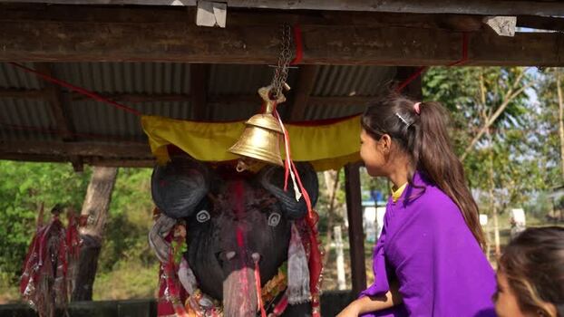 View of a woman at a shrine with a brass bell and statue Nepal.