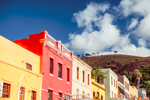 View of the iconic colorful houses in the Bo Kaap neighborhood with Signal Hill in the background under a blue sky Cape Town Western Cape South Africa. View of the iconic colorful houses in the Bo Kaap neighborhood with Signal Hill in the background under a blue sky Cape Town Western Cape South Africa.