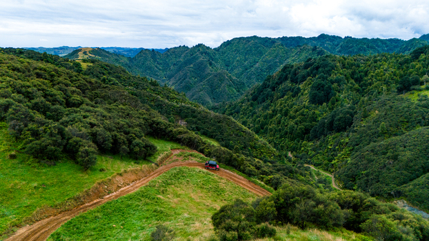 Aerial view of a lone RV winding through lush green hills and valleys at Blue Duck Station Retaruke Manawatu Whanganui Region New Zealand. Aerial view of a lone RV winding through lush green hills and valleys at Blue Duck Station Retaruke Manawatu Whanganui Region New Zealand.