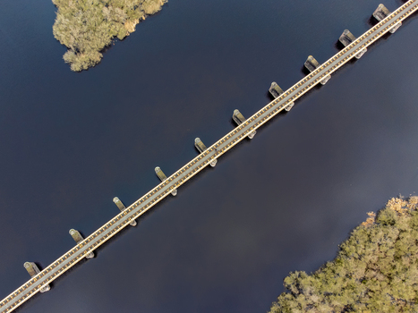 Aerial view of the Moerputtenbrug cutting across the still waters flanked by verdant islets a stark contrast of dark water and bright foliage s Hertogenbosch North Brabant Netherlands.