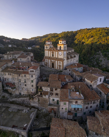 Aerial view of the Santa Maria Assunta church nestled among historic stone rooftops and lush hills in the town of Artena Lazio Italy.