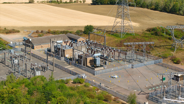 Aerial view of Eaton Socon Substation with electrical transformers switchgear and power lines surrounded by agricultural fields and trees in St. Neots England United Kingdom. Aerial view of Eaton Socon Substation with electrical transformers switchgear and power lines surrounded by agricultural fields and trees in St. Neots England United Kingdom.