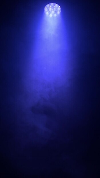 View of a blue spotlight shining through thick smoke.