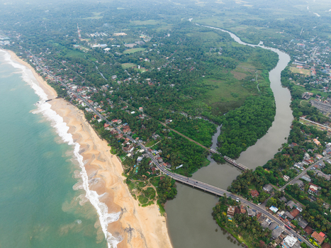 Aerial view of the coastline featuring a sandy beach a river mouth and lush tropical vegetation in Galle Southern Province Sri Lanka. Aerial view of the coastline featuring a sandy beach a river mouth and lush tropical vegetation in Galle Southern Province Sri Lanka.