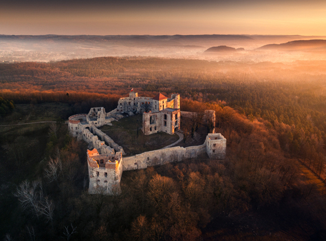 Aerial view of the historic Tenczyn Castle ruins on a forested hill during a misty golden hour sunset over the Krakow Czestochowa Upland Krakow County Lesser Poland Poland. Aerial view of the historic Tenczyn Castle ruins on a forested hill during a misty golden hour sunset over the Krakow Czestochowa Upland Krakow County Lesser Poland Poland.