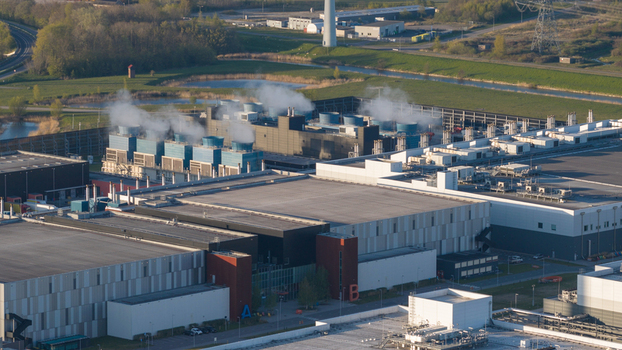 Aerial view of the Google Data Center featuring cooling towers with steam and modern industrial buildings surrounded by green fields in Eemshaven Groningen Netherlands. Aerial view of the Google Data Center featuring cooling towers with steam and modern industrial buildings surrounded by green fields in Eemshaven Groningen Netherlands.