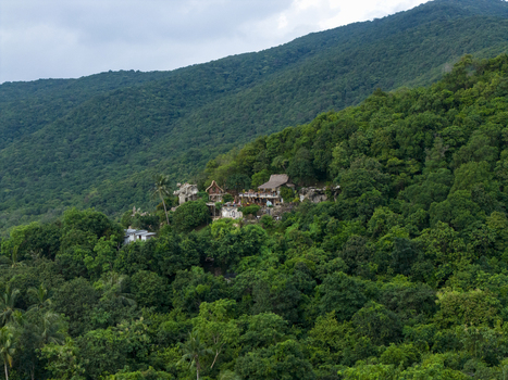Aerial view of verdant mountain slopes blanketed in dense tropical foliage dotted with rustic dwellings at Bukit Love Karimunjawa Jawa Tengah Indonesia. Aerial view of verdant mountain slopes blanketed in dense tropical foliage dotted with rustic dwellings at Bukit Love Karimunjawa Jawa Tengah Indonesia.