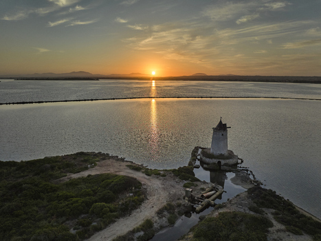 Aerial view of the historic windmill at Saline dello Stagnone during a golden sunset with calm salt pan waters reflecting the light in Marsala Sicilia Italy. Aerial view of the historic windmill at Saline dello Stagnone during a golden sunset with calm salt pan waters reflecting the light in Marsala Sicilia Italy.