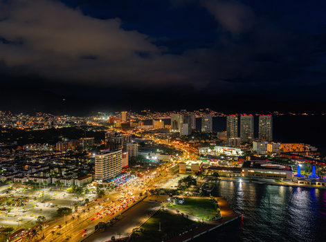 Aerial view of the illuminated Zona Hotelera in Puerto Vallarta at night featuring coastal hotels city lights and the Pacific Ocean coastline. Puerto Vallarta Jalisco Mexico.