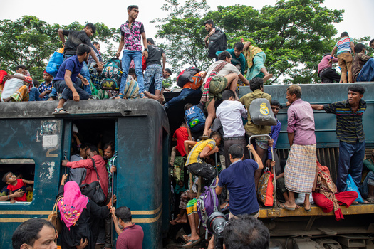 Dhaka Bangladesh 15 June 2018 View of crowds of people climbing onto the roof and hanging from the doors of a train at Airport Railway Station. Dhaka Bangladesh 15 June 2018 View of crowds of people climbing onto the roof and hanging from the doors of a train at Airport Railway Station.
