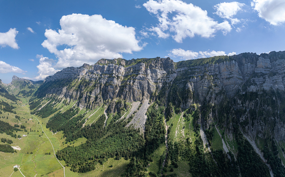 Aerial view of the Justistal valley and the dramatic limestone cliffs of the Niederhorn mountain range with lush green alpine meadows in Sigriswil Bern Switzerland. Aerial view of the Justistal valley and the dramatic limestone cliffs of the Niederhorn mountain range with lush green alpine meadows in Sigriswil Bern Switzerland.