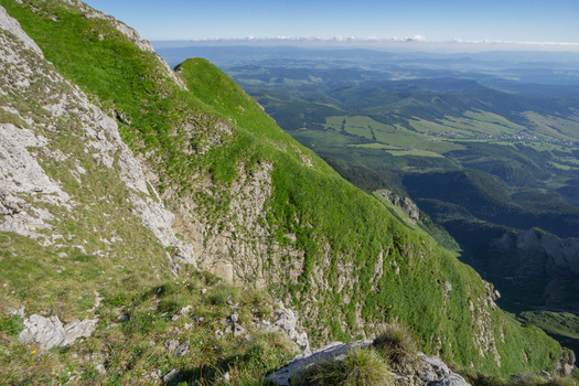 View of the steep grassy slopes of Zdiarska vidla in the Belianske Tatry mountains overlooking a vast valley and distant hills in Zdiar Presov Region Slovakia. View of the steep grassy slopes of Zdiarska vidla in the Belianske Tatry mountains overlooking a vast valley and distant hills in Zdiar Presov Region Slovakia.