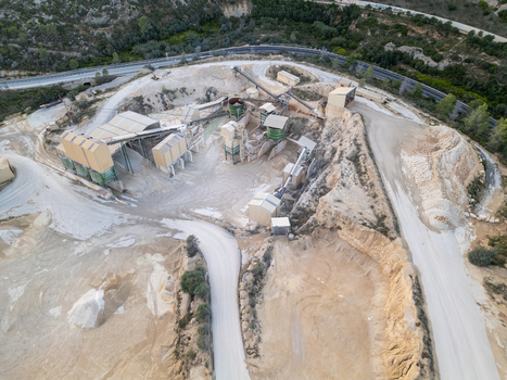 Aerial view of an industrial quarry site with processing buildings conveyor belts and excavated terrain in Teulada Valencian Community Spain.