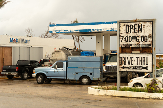 San Jose Tinian Northern Mariana Islands 05 July 2026 View of a gas station with a Mobil Mart store a utility truck and a sign showing operating hours in a weathered urban setting. San Jose Tinian Northern Mariana Islands 05 July 2026 View of a gas station with a Mobil Mart store a utility truck and a sign showing operating hours in a weathered urban setting.