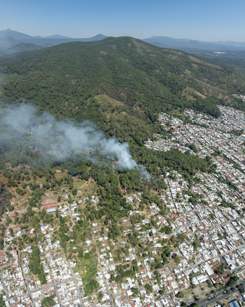 Aerial view of a wildfire burning in the forest near the urban residential area of Uruapan Michoacan Mexico.