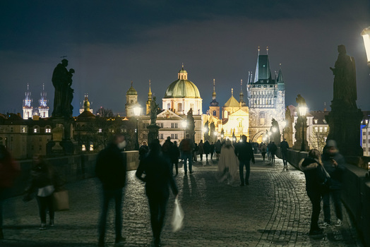 Prague Prague Czechia 03 November 2021 View of Charles Bridge at night with illuminated historic architecture and people walking on the cobblestone path. Prague Prague Czechia 03 November 2021 View of Charles Bridge at night with illuminated historic architecture and people walking on the cobblestone path.