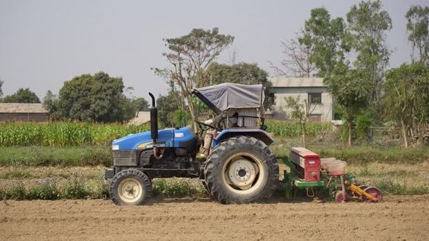 View of a blue tractor working in a rural field Nepal. View of a blue tractor working in a rural field Nepal.